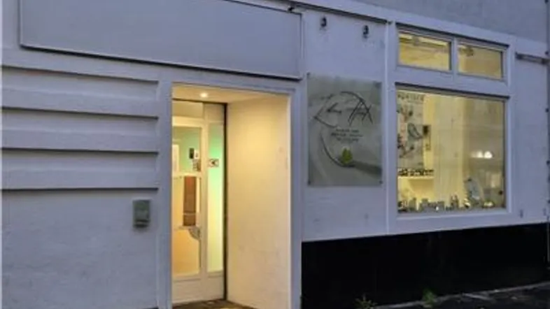 Außenansicht eines Geschäftsgebäudes mit Eingangstür und Schaufenster, das Produkte zeigt.