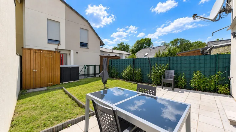 Gemütliche Terrasse mit Gartenmöbeln und kleinem Rasenbereich hinter dem Haus.