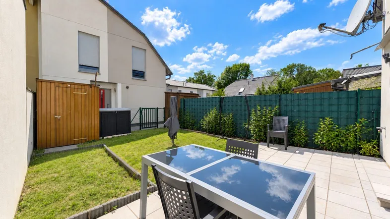 Gepflegter Gartenbereich mit Rasenfläche und einer möblierten Terrasse für entspannte Stunden im Freien.