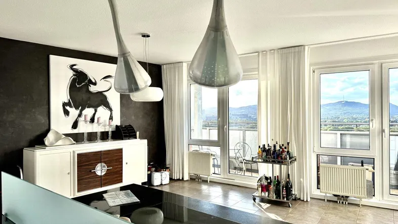Helles Esszimmer mit modernem Sideboard, Kunstwerk und Zugang zu großen Fenstern mit Bergblick.