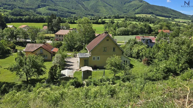Haus in ländlicher Umgebung mit grünen Hügeln und Bäumen, umgeben von Natur und Weitblick.