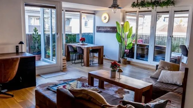 Heller Wohn- und Essbereich mit Holzboden, gemütlichem Sofa und Zugang zu einem Balkon.