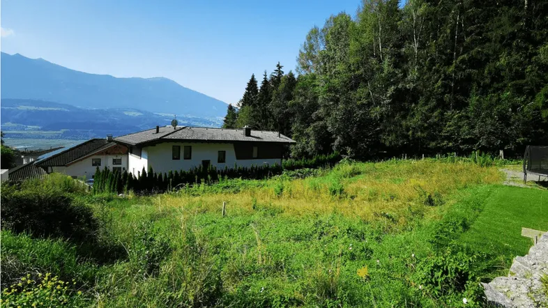 Haus in ländlicher Umgebung mit weitem Blick auf die Berge und viel Grünfläche.