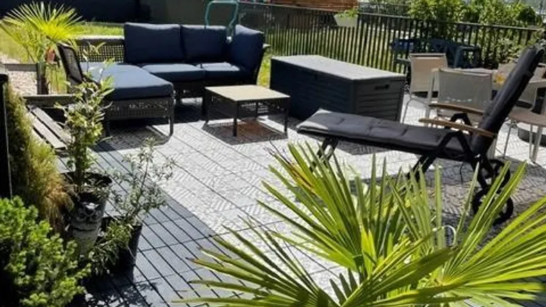 Geräumige Terrasse mit modernen Gartenmöbeln, Sonnenschirm und Pflanzen, ideal zum Entspannen im Freien.