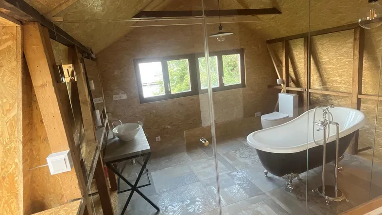 Dachgeschoss-Badezimmer mit freistehender Badewanne, Waschtisch und gemusterten Bodenfliesen unter schräger Decke.
