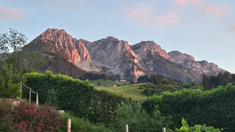 Panoramablick auf die Berge mit grünen Hügeln und Wäldern bei Sonnenuntergang.