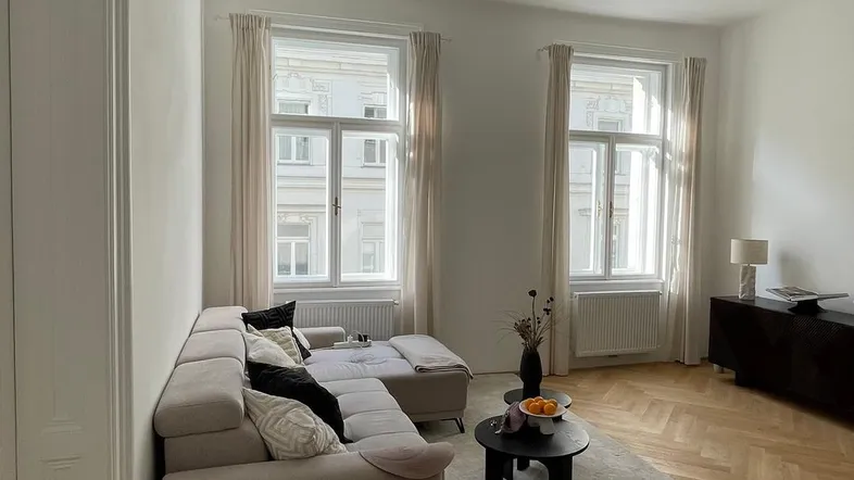 Helles Wohnzimmer mit modernem Sofa, Couchtisch und Fischgrätparkett.