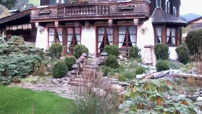 Traditionelles Holzchalet mit mehreren Balkonen und einem gepflegten Gartenbereich.