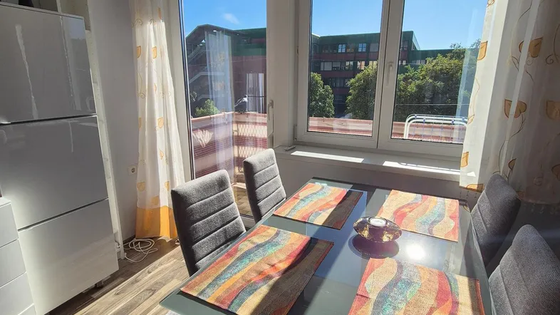 Heller Essbereich mit modernem Glastisch, bequemen Stühlen und Blick ins Grüne.