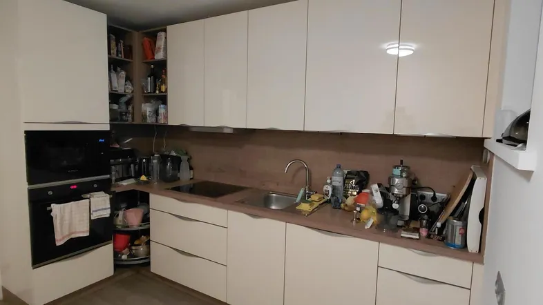 Moderne Küche mit hellen Schränken, integriertem Backofen und viel Stauraum für Küchenutensilien.