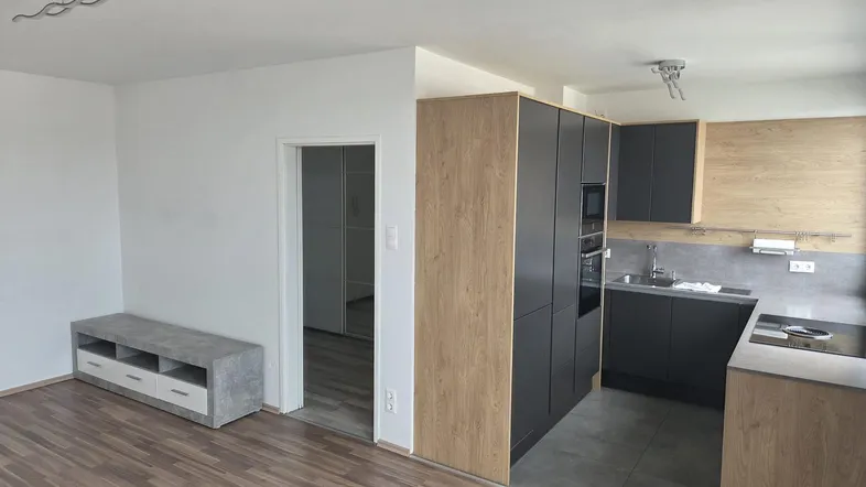 Heller offener Wohnbereich mit moderner Einbauküche und Laminatboden, ideal für geselliges Beisammensein.
