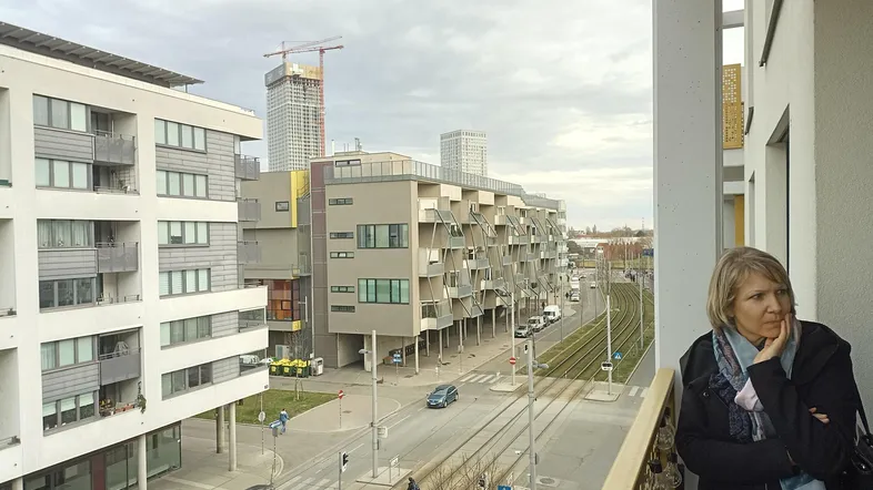 Blick vom Balkon auf die belebte Straße mit modernen Gebäuden und einer Baustelle in der Ferne.