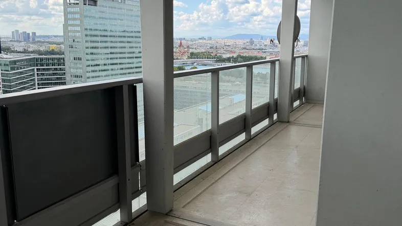 Geräumiger Balkon mit Fliesenboden und weitem Blick über die Stadtlandschaft und den Himmel.
