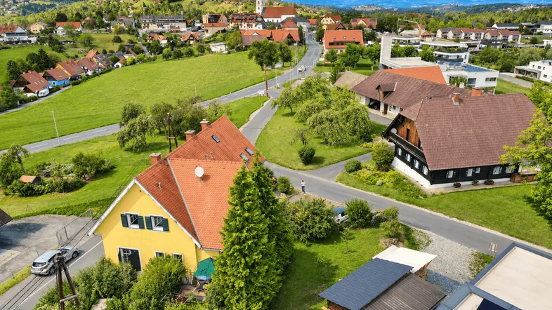 Luftaufnahme eines charmanten Dorfes mit grünen Feldern und traditionellen Häusern.