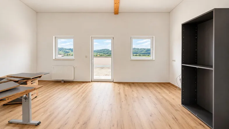 Heller, leerer Raum mit Laminatboden, weißen Wänden und einem Holzbalken an der Decke.