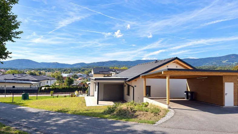 Modernes Einfamilienhaus mit Carport und Garage in ländlicher Umgebung mit Bergblick.