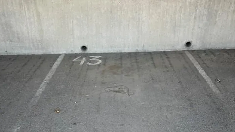 Parkplatz Nummer 43 mit Betonwand und Markierungen auf dem Asphalt.