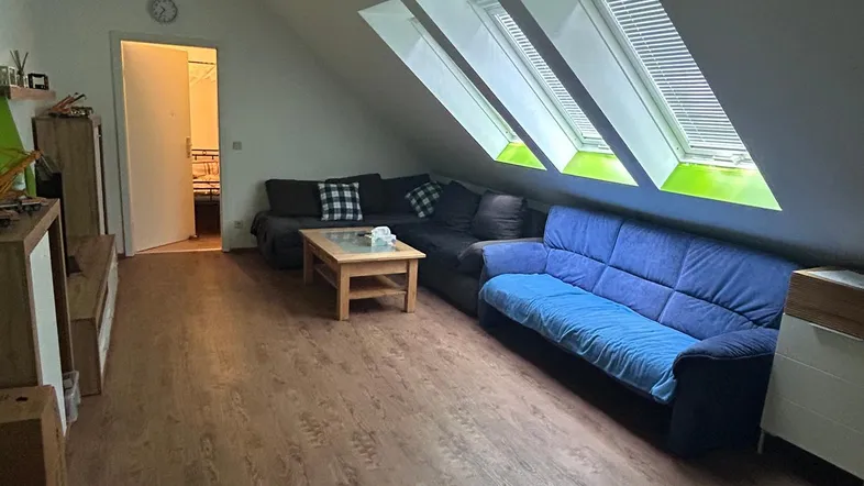 Gemütliches Wohnzimmer im Dachgeschoss mit Schrägen, Laminatboden und drei Dachfenstern.