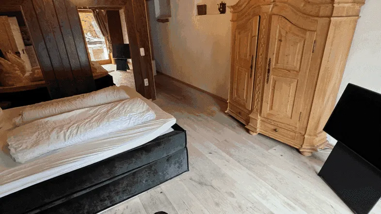 Gemütliches Schlafzimmer im alpinen Stil mit Holzbalkendecke, hellem Holzboden und rustikalem Kleiderschrank.