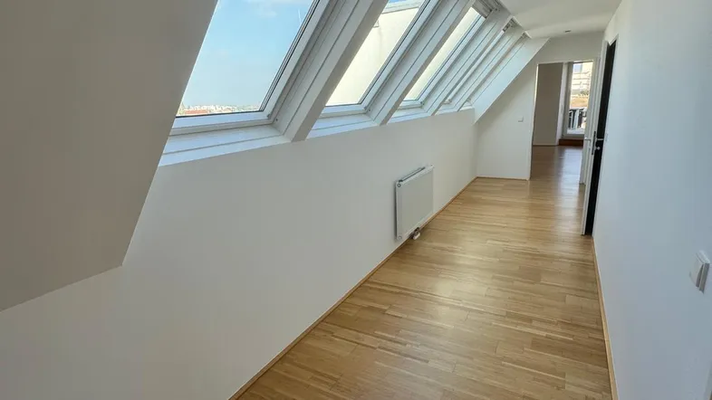 Heller Flur mit Holzparkettboden und mehreren Dachfenstern, die viel Tageslicht hereinlassen.