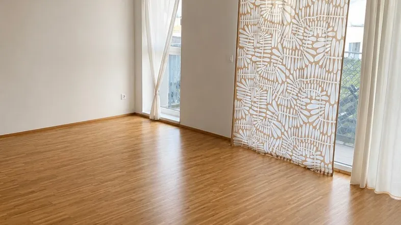 Helles, leeres Zimmer mit Parkettboden und Zugang zu einem Balkon, bereit zur individuellen Gestaltung.