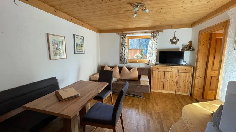 Gemütlicher Wohn-Essbereich mit Holzbalkendecke, Parkettboden und traditionellen Möbeln.