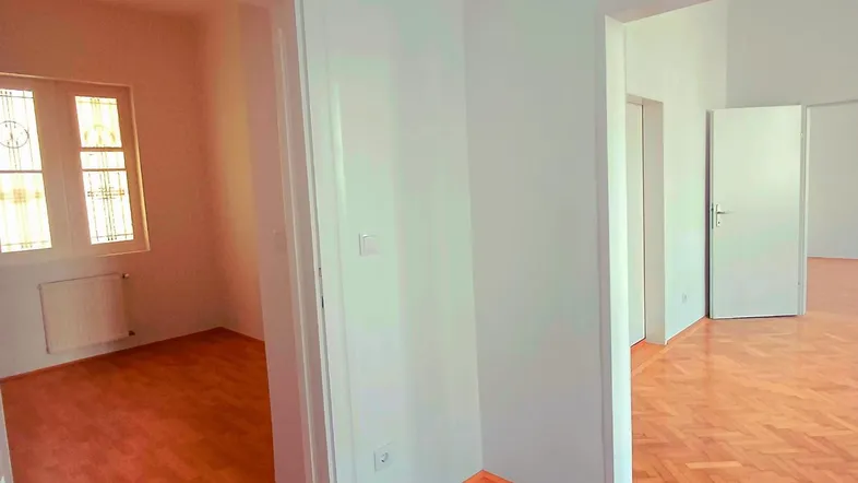 Heller Raum mit Fischgrätparkettboden und weißen Wänden, bereit für die individuelle Gestaltung.