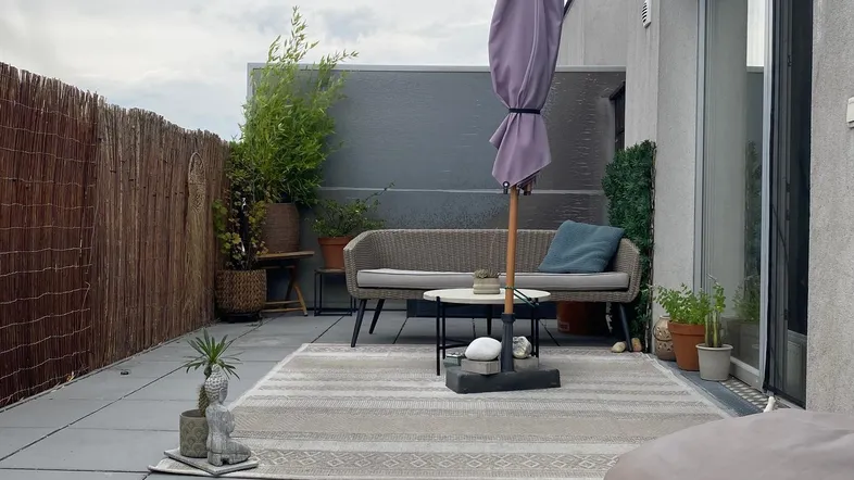 Große Dachterrasse mit bequemen Gartenmöbeln, Sonnenschirm und Pflanzen für entspannte Stunden.