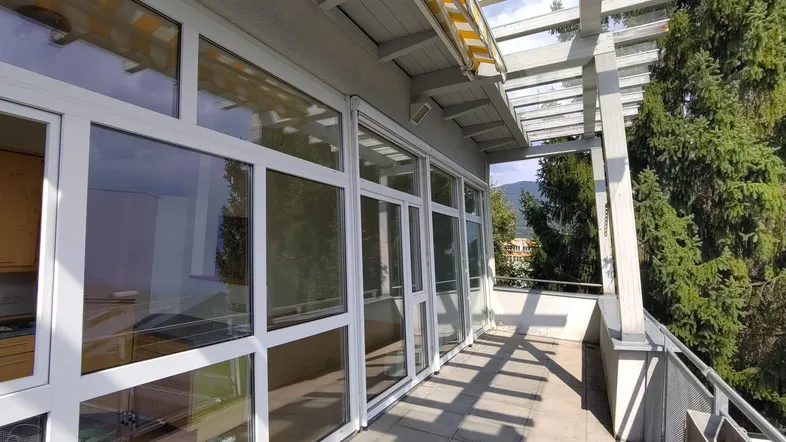 Geräumige Terrasse mit Pergola, Markise und großen Fenstern zum Innenbereich.