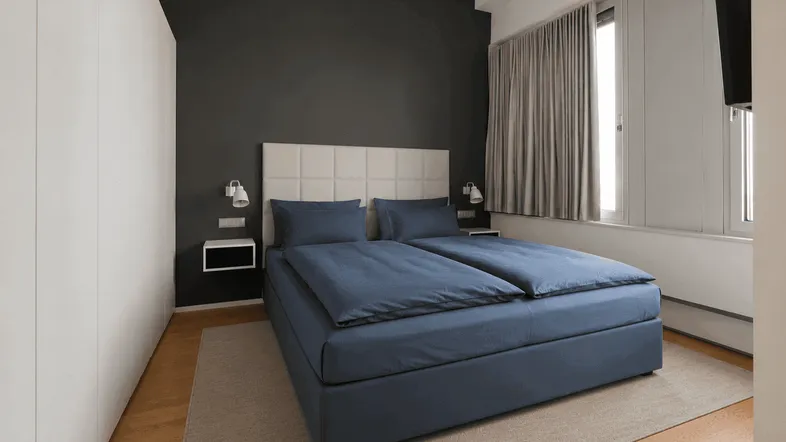 Modernes Schlafzimmer mit dunkler Akzentwand, großem Bett und integrierten Nachttischen.
