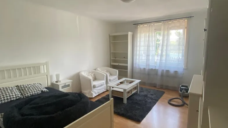 Helles Schlafzimmer mit Holzboden, einem großen Bett und einer gemütlichen Sitzecke am Fenster.