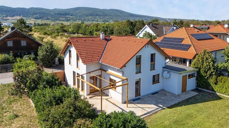 Freistehendes Einfamilienhaus mit rotem Ziegeldach, Terrasse und Garten in ländlicher Umgebung.