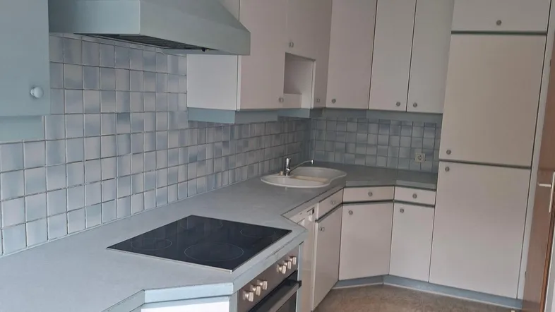 Küche mit hellblauen und weißen Schränken, integriertem Kochfeld und Backofen.