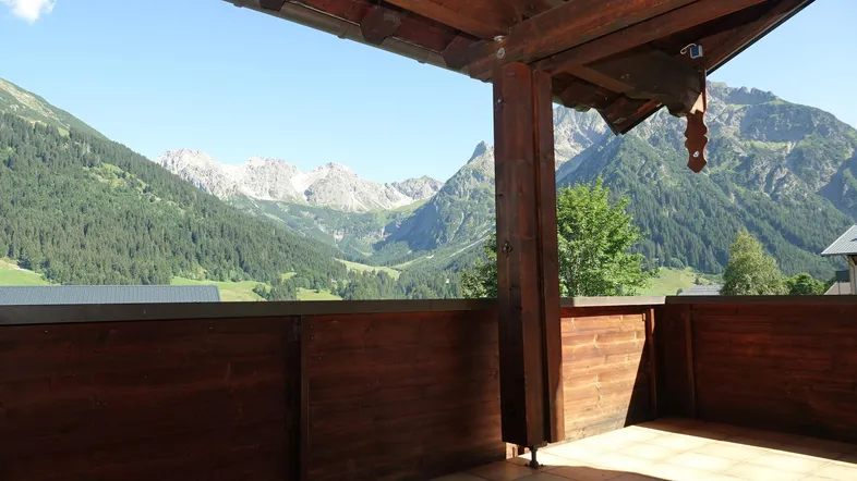 Geräumiger Balkon mit Holzelementen und atemberaubendem Blick auf die umliegende Berglandschaft.