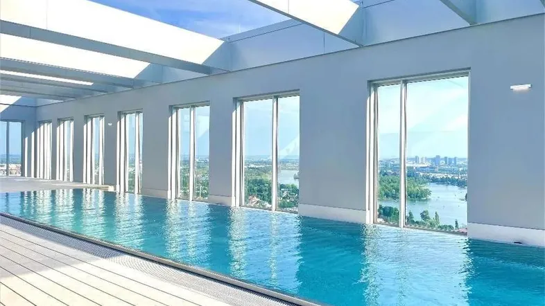 Helles Hallenbad mit Panoramablick auf die Stadt und den Fluss, ideal für Wellness und Entspannung.
