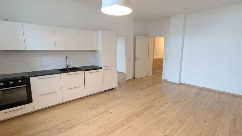 Moderne offene Küche mit weißen Schränken, dunkler Arbeitsplatte und hellem Holzfußboden.