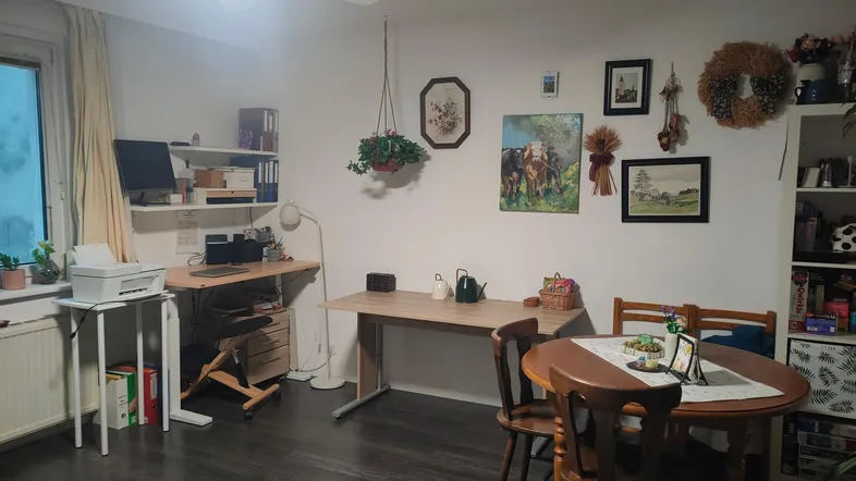Helles Wohnzimmer mit dunklem Laminatboden, Deckenventilator, Arbeitsbereich und Esstisch.