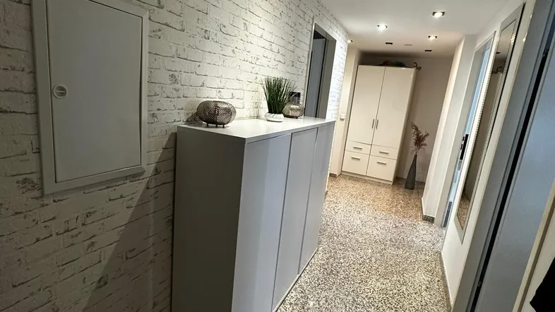 Heller Flur mit moderner Ziegelsteinoptik-Tapete und praktischem Schuhschrank.