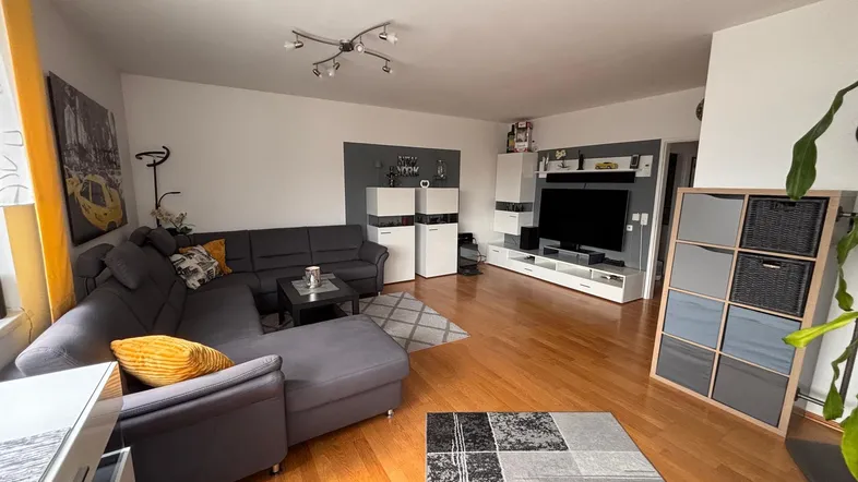Geräumiges Wohnzimmer mit bequemer Eckcouch, Holzboden und modernem Entertainment-System.
