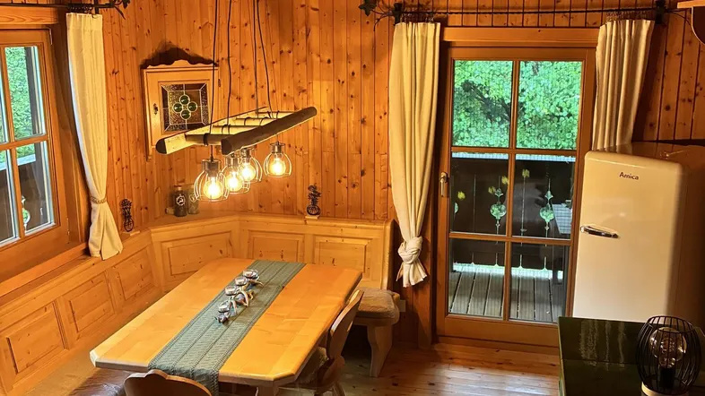 Gemütlicher Essbereich mit Holztäfelung, Eckbank und Zugang zum Balkon, ideal für Mahlzeiten.
