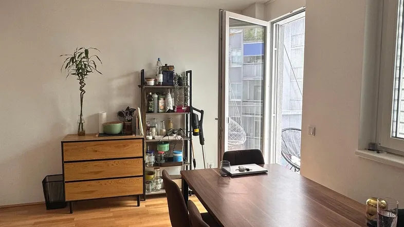 Heller Essbereich mit Holzboden und Zugang zu einem Balkon, ideal für gemeinsame Mahlzeiten.