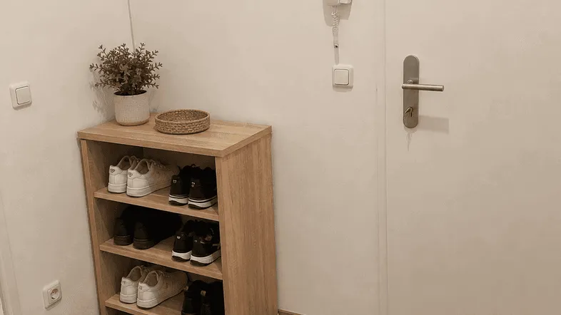 Heller Eingangsbereich mit praktischem Schuhregal, Gegensprechanlage und Laminatboden.