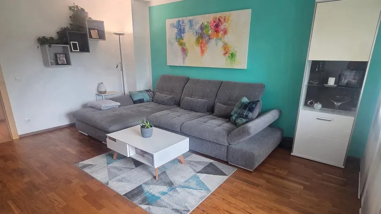 Modernes Wohnzimmer mit bequemer Eckcouch, Holzboden und farbenfroher Wandgestaltung.