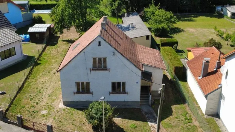 Luftaufnahme eines Einfamilienhauses mit rotem Ziegeldach und umliegendem Grundstück in ländlicher Umgebung.