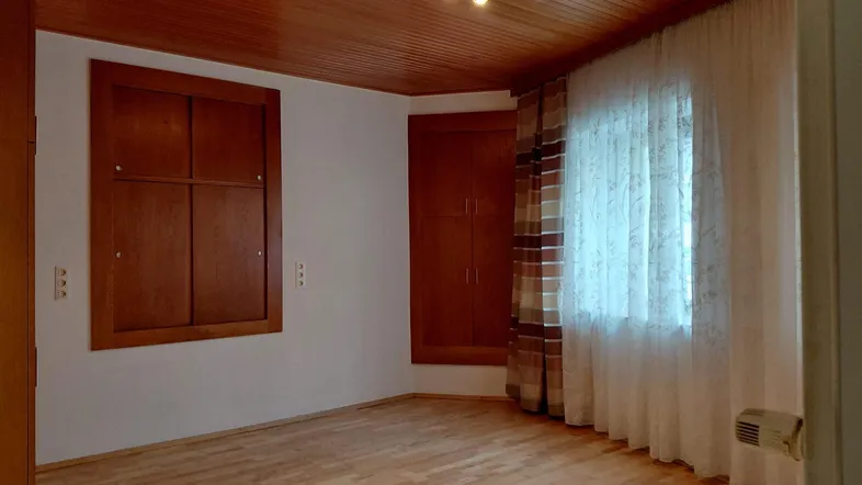 Geräumiges Schlafzimmer mit Holzdecke, Parkettboden und integrierten Holzschränken.