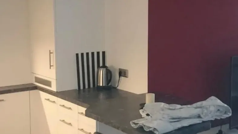 Funktionale Küche mit weißen Schränken, dunkler Arbeitsplatte und integrierter Frühstücksbar.