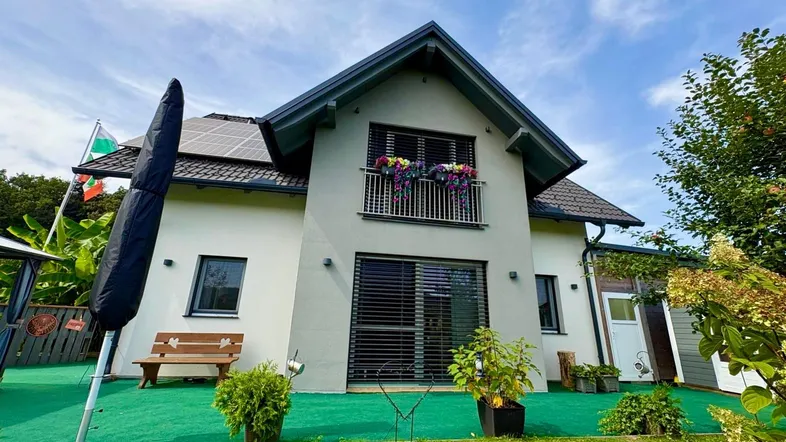 Modernes Einfamilienhaus mit Photovoltaikanlage, kleinem Balkon und gepflegtem Vorgarten.