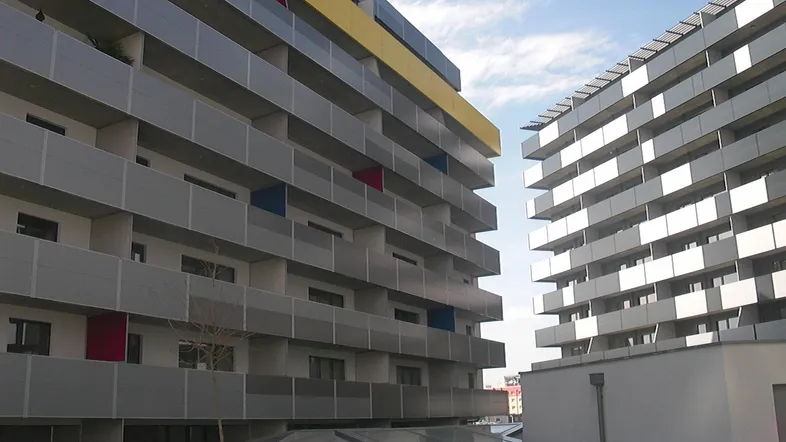 Moderne Wohngebäude mit zahlreichen Balkonen und farbigen Akzenten unter blauem Himmel.