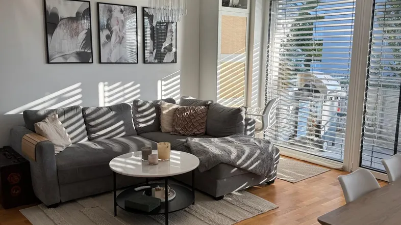 Helles Wohnzimmer mit modernem Ecksofa, Couchtisch und Zugang zum sonnigen Balkon.