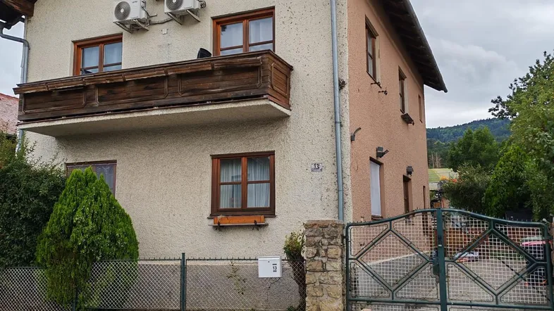 Fassade eines Hauses mit Balkon, Klimaanlagen-Außengeräten und einem Gartentor.